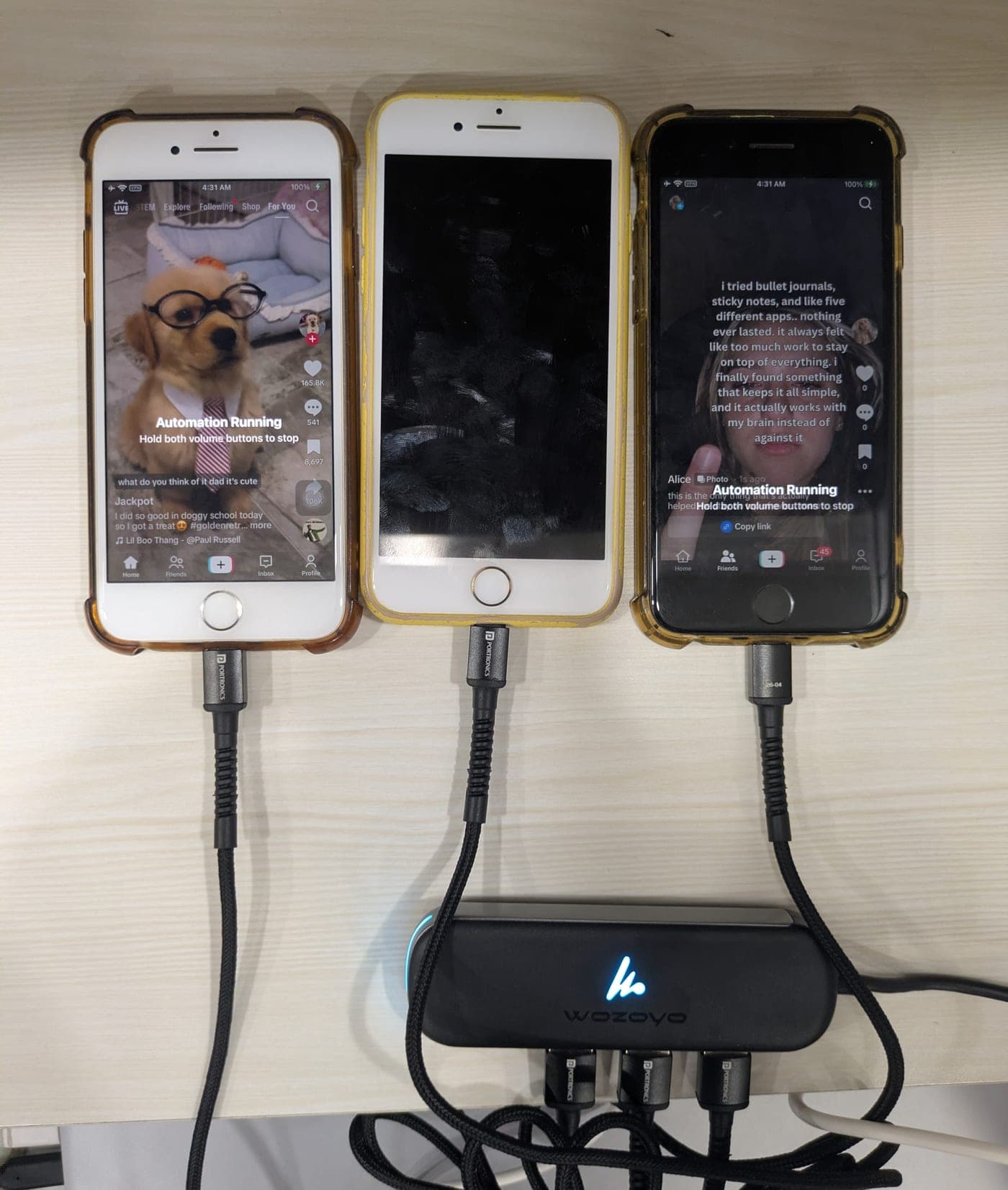 Three iPhones on a desk connected to a powered USB hub, running iOS Farm automation